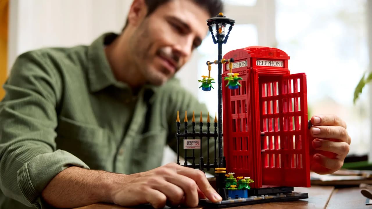 A man building a red Lego telephone box.