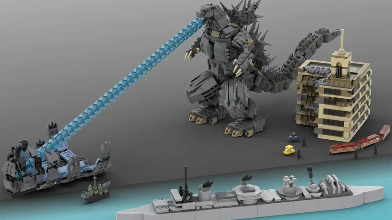 A Lego Godzilla breathing blue flame, with a battleship and a city block next to them.