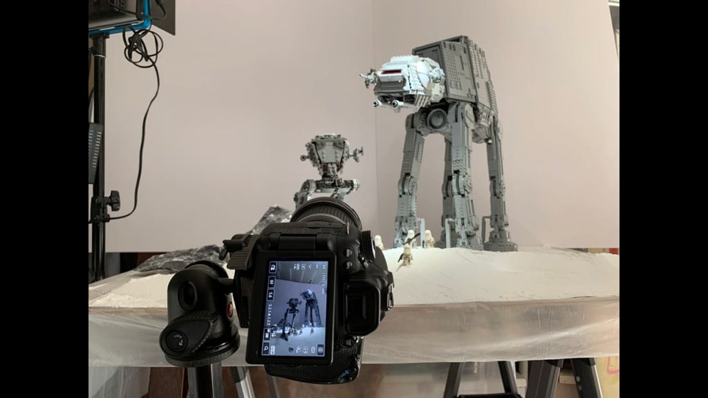 A behind-the-scenes shot of a Lego AT-AT and AT-ST being photographed. 